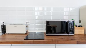 A kitchen with a white toaster, a black tablet, and a black microwave on a wooden countertop. - APT Rome 5 BDRM’s (Roma)