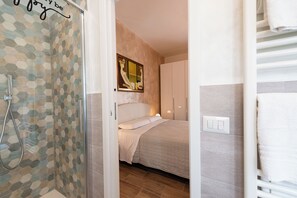 A bedroom with a shower, a bed, and a painting on the wall. - Beautiful, modern three-room apartment for 4 people, with 2 bedrooms, 2 bathrooms, a laundry room, and a parking space (Perugia)