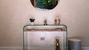 A modern bathroom with a glass vanity, a small potted plant, and a decorative gold statue.