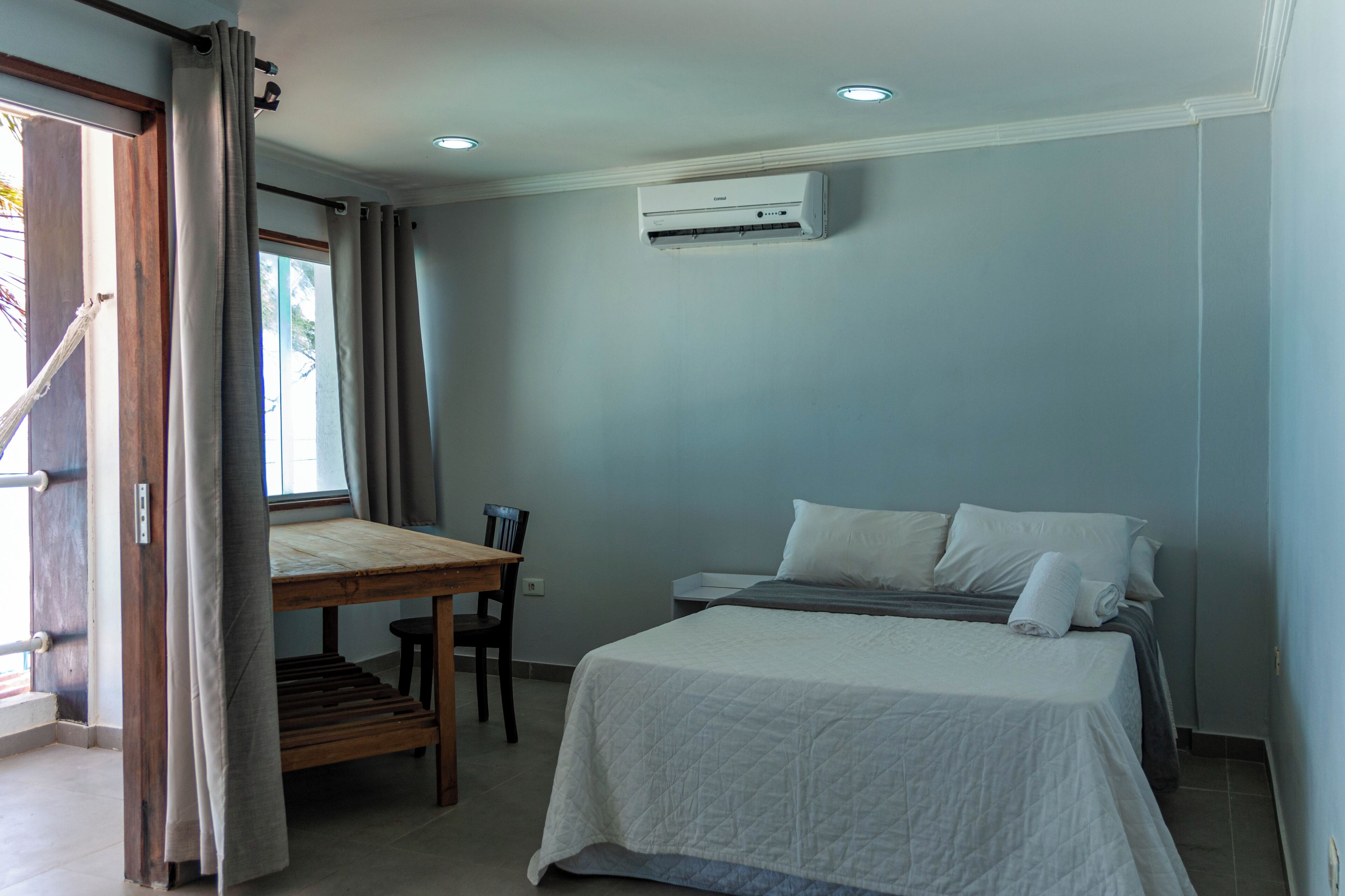 Un dormitorio con cama, escritorio y aire acondicionado.