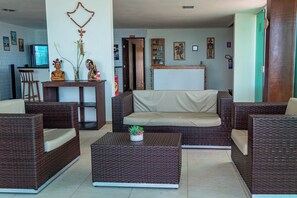 A living room with wicker furniture, a television, and decorative items. - Pousada La Bella Luna (Ipojuca)