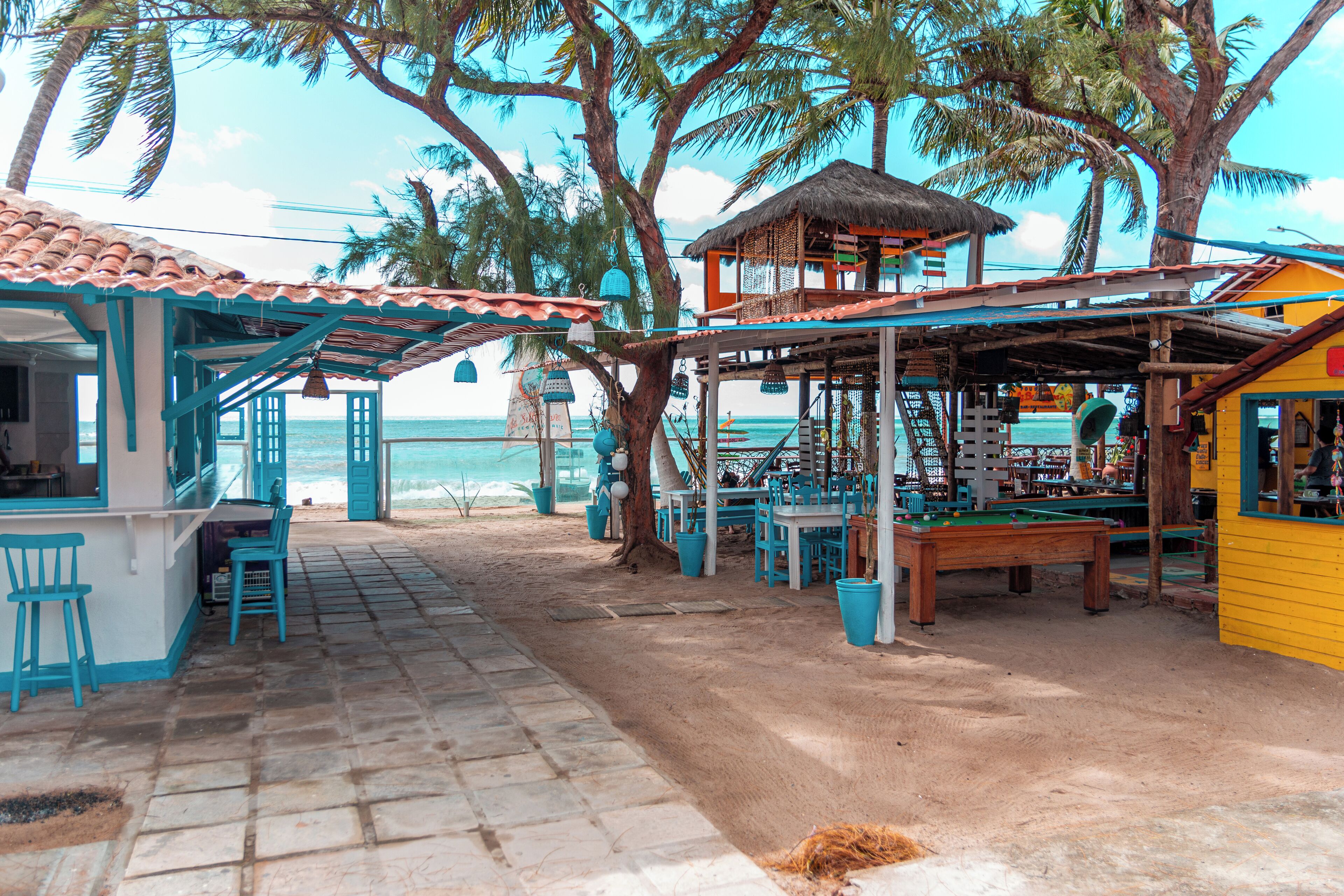 Un bar en la playa con terraza y una mesa de billar.