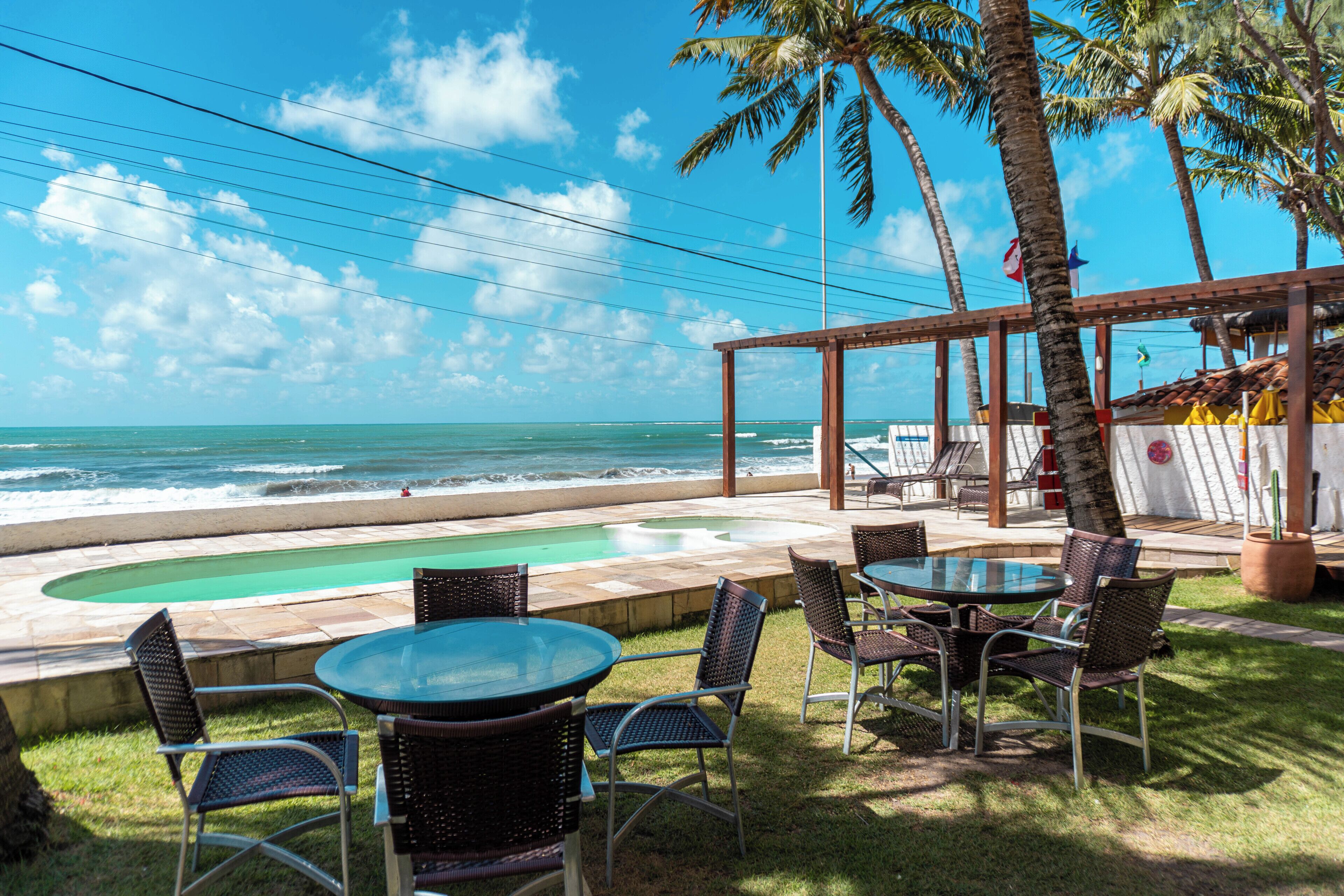A poolside area with chairs and tables, overlooking the ocean.