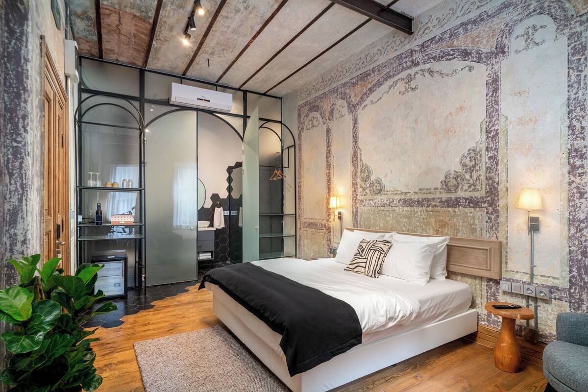 A bedroom with a large bed, a wooden ceiling, and a rustic wall.