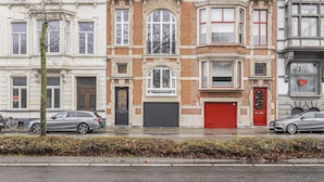 A row of multi-story buildings with distinct architectural styles, including a red door and a garage. - Ribas Guestrooms (Bruges)