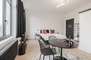 A modern hotel room with a bed, a dining table, and a radiator. - Ribas Guestrooms (Bruges)