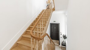 A wooden staircase with a handrail, white walls, and a black door at the bottom. - Ribas Guestrooms (Bruges)
