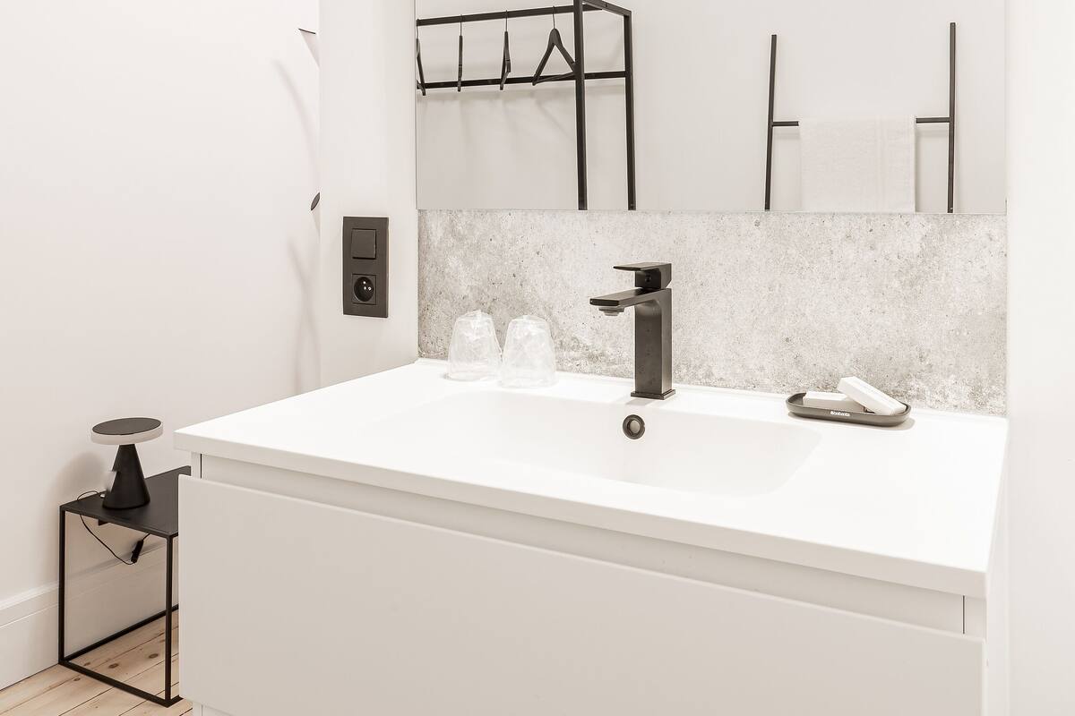 A modern bathroom with a white vanity, a large mirror, and a towel rack.