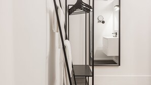 A modern interior with a black metal rack holding white towels, a mirror reflecting a bathroom, and a wooden floor. - Ribas Guestrooms (Bruges)