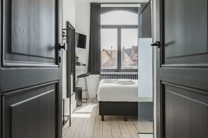 A bedroom with a bed, a radiator, a TV, and a window with curtains. - Ribas Guestrooms (Bruges)