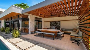 Une terrasse extérieure avec une piscine, une pergola en bois, un chemin en pierre et des meubles modernes.