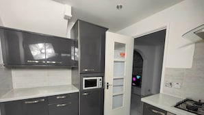 A modern kitchen with dark cabinets, a microwave, and a gas stove. - Tyburn House, Birmingham B24 with FREE Parking and FREE WiFi (West Midlands)