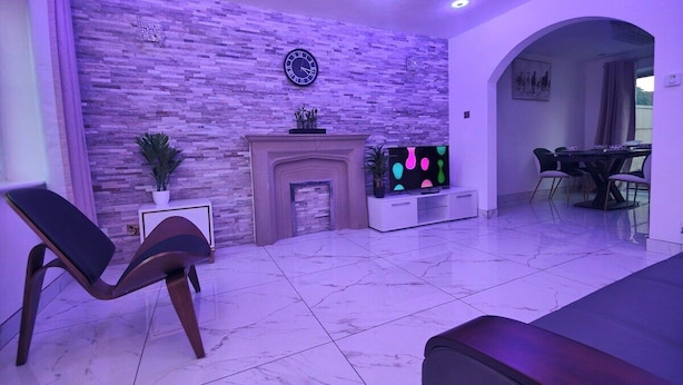 A modern living room with a fireplace, a TV, and a dining area. - Tyburn House, Birmingham B24 with FREE Parking and FREE WiFi (West Midlands)