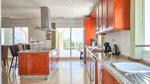 A spacious kitchen with granite countertops, wooden cabinets, and a central island. - 5 bed villa with pool in Cerros de Aguila (Mijas Costa)