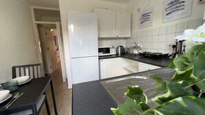 Eine moderne Küche mit weißen Schränken, einer schwarzen Arbeitsplatte und einem Essbereich mit Tisch und Stühlen.