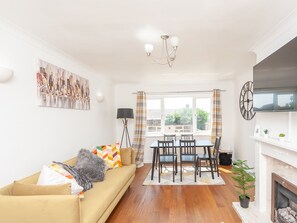 Relax in this stylish living space with a sofa, dining area, fireplace, and large windows offering a view.