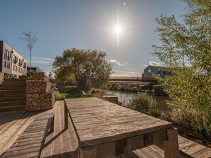 A wooden deck with a stone wall and steps leading to a modern building.