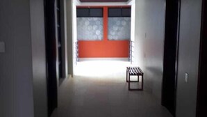 A hallway with a bench, a red accent wall, and a window with blinds. - 9 Estrellas Hotel (Comitan de Dominguez)