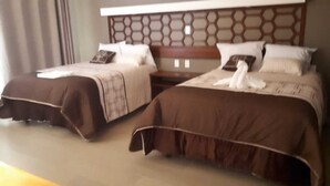 A hotel room with two beds, each with a brown bedspread and white pillows. - 9 Estrellas Hotel (Comitan de Dominguez)