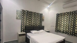 A bedroom with a bed, nightstands, a ceiling fan, patterned curtains, and a marble floor. - One bedroom apartment East legon  (Accra)