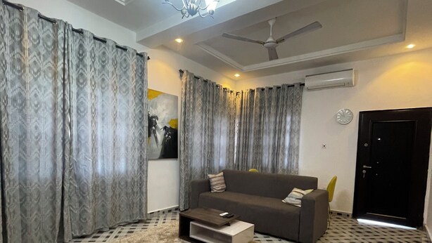 A living room with a sofa, a coffee table, a patterned rug, and a checkered floor. - One bedroom apartment East legon  (Accra)