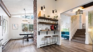 A modern kitchen with wooden flooring, a brick accent wall, and a dining area with a bench. - Stunning Lakefront Oasis—Hot Tub, Beach & Luxury! (E Wakefield)