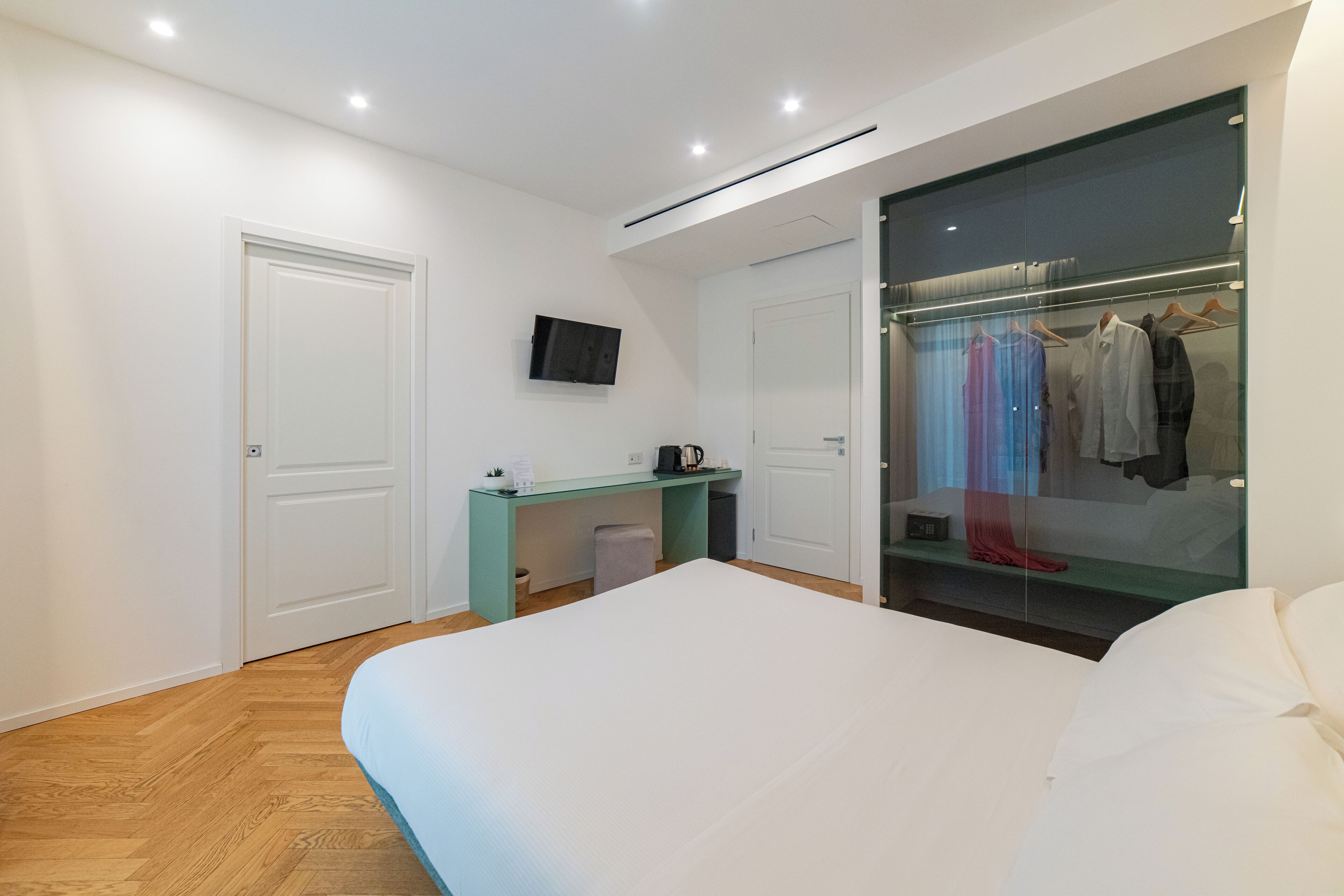 Une chambre avec un lit, un bureau, une armoire et un téléviseur fixé au mur.