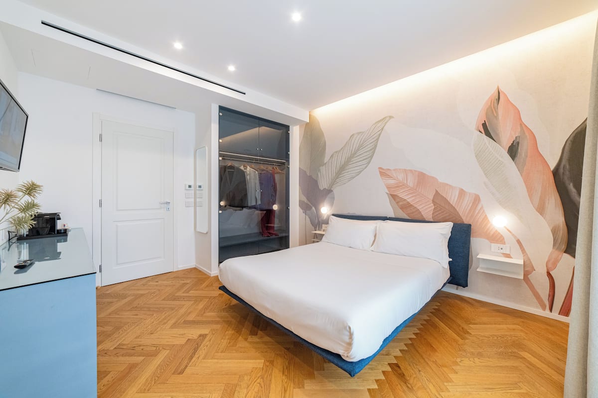 A modern bedroom with a bed, a wardrobe, and a wall with a leaf pattern.