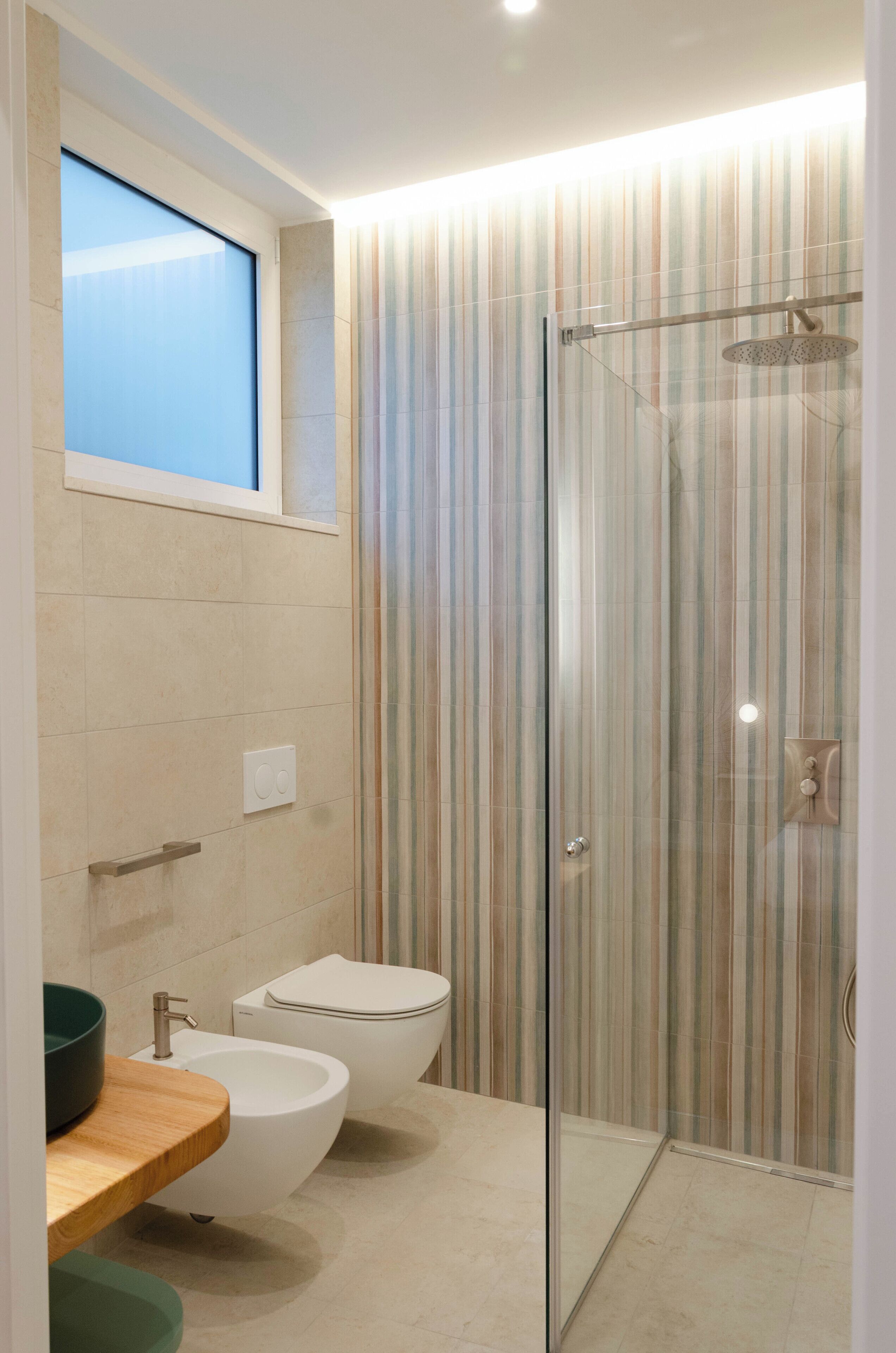 Een moderne badkamer met een glazen douchecabine, een bidet en een wastafel met een houten blad.