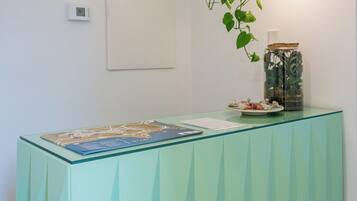 A reception desk with a glass top, a wall-mounted light fixture, a security camera, and a wall-mounted thermostat.