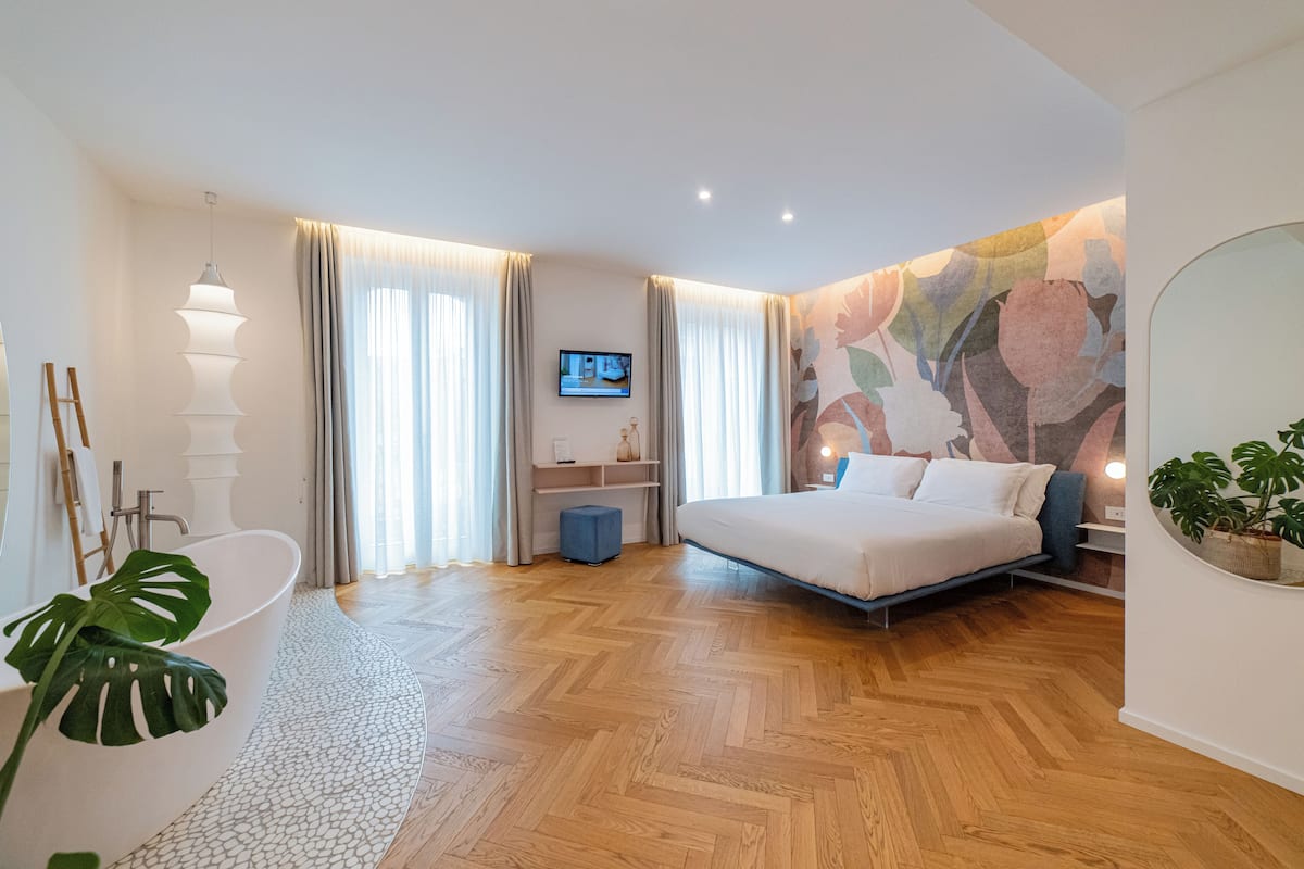 A modern bedroom with a large bed, a built-in TV, and a bathroom with a bathtub.