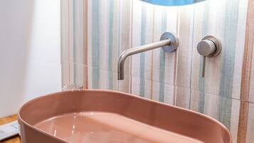 A bathroom with a pink sink, a wooden countertop, and a striped tile backsplash.