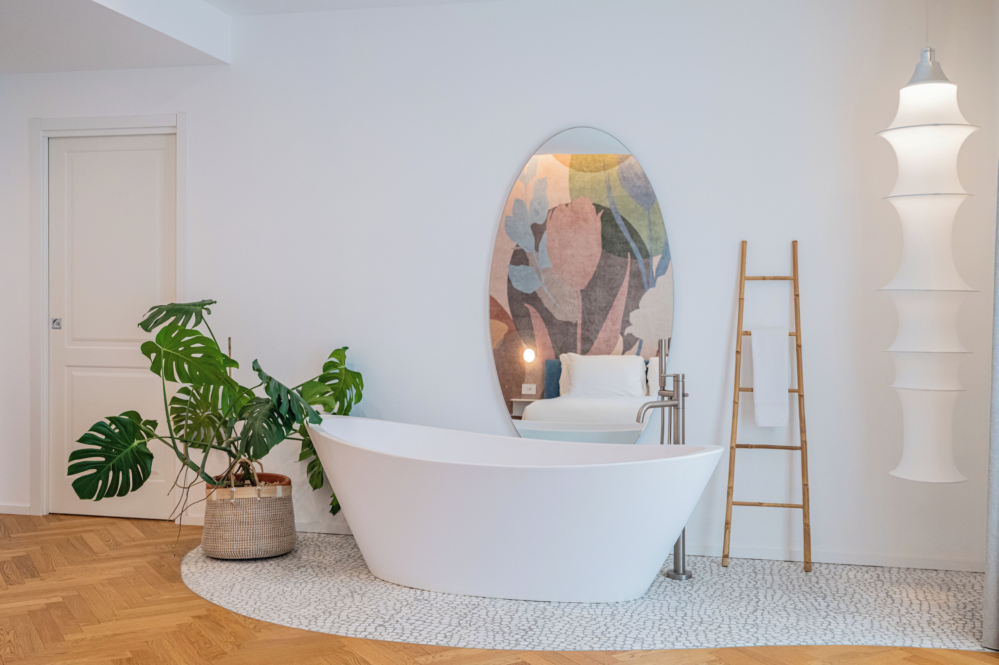 Une salle de bain moderne avec une baignoire sur pieds, un grand miroir, un lavabo et une plante en pot.