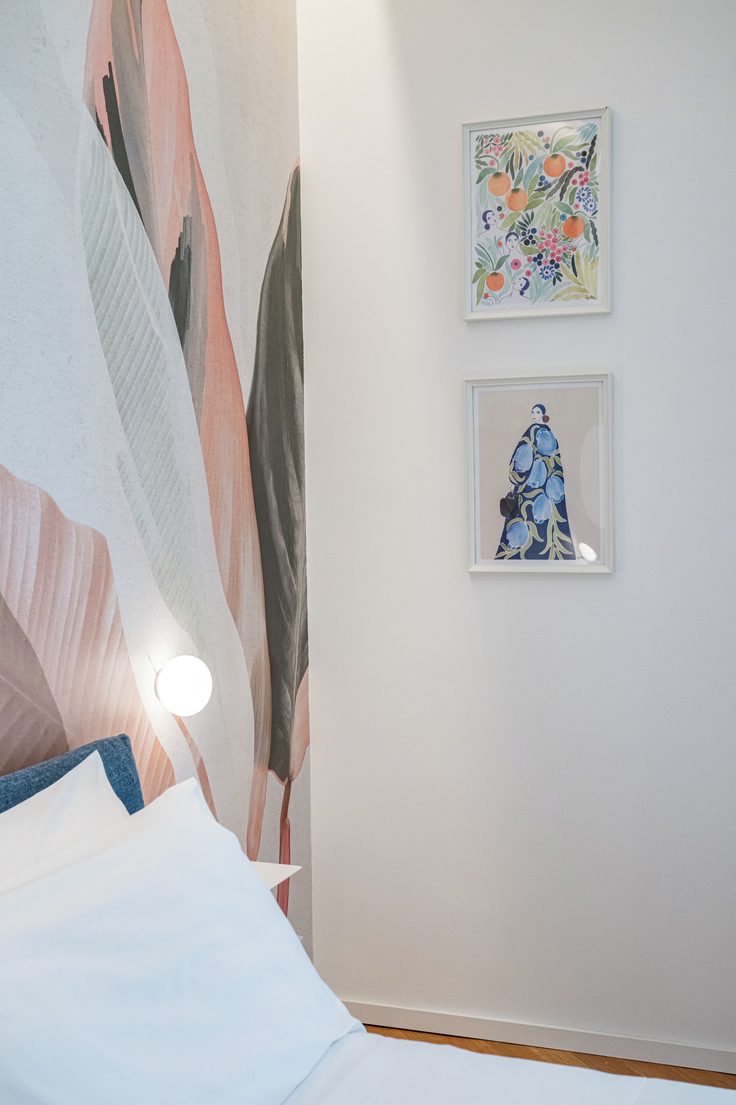 Un dormitorio con una cama, un cuadro abstracto grande y dos obras de arte enmarcadas en la pared.