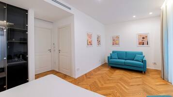 A modern bedroom with a large bed, a teal sofa, and a wardrobe.