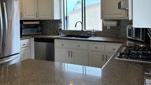 A modern kitchen with white cabinets, a stainless steel refrigerator, a built-in oven, and a granite countertop. - Ocean View Condo w/ Beach Access!Walk to Del Mar Track/Fair & Solana Train Stop (Solana Beach)