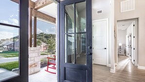 A modern interior with a large glass door leading to a balcony, a wooden floor, and a hallway with white doors. - Escape to paradise in Texas Hill Country (Harker Heights)