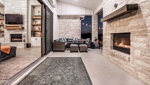 A cozy living room with a stone fireplace, a comfortable seating area, and a television mounted on the wall. - Escape to paradise in Texas Hill Country (Harker Heights)