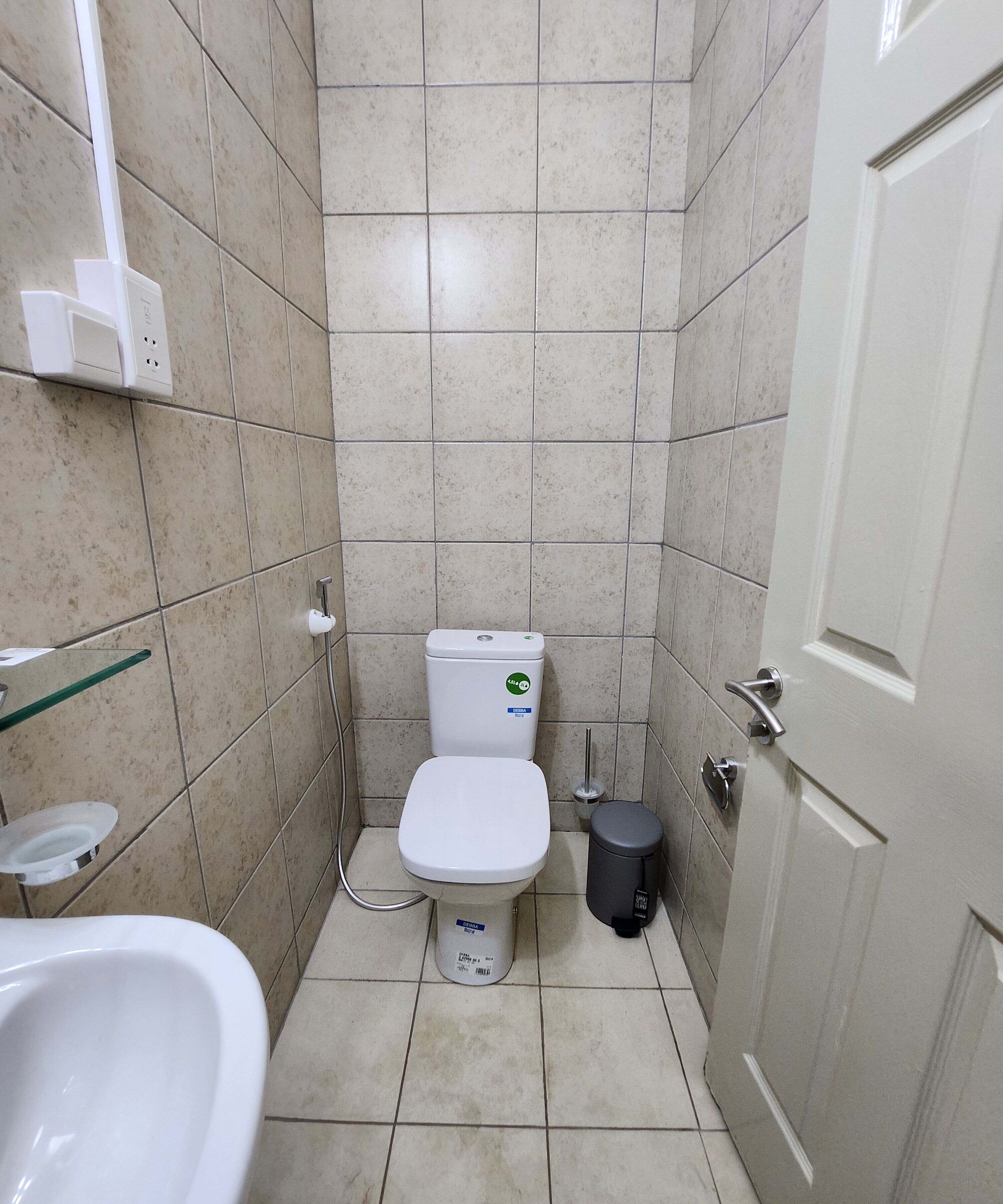 A small, tiled bathroom with a toilet, bidet, and a trash bin.