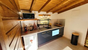 Eine moderne Küche mit Holzbalken, einer eingebauten Mikrowelle, einem Spülbecken und einem kleinen Kühlschrank.