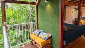 Eine Holzterrasse mit einem Bett und einer Bank, umgeben von üppiger Vegetation.
