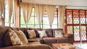 A living room with a brown leather sofa, beige curtains, and a wooden coffee table.