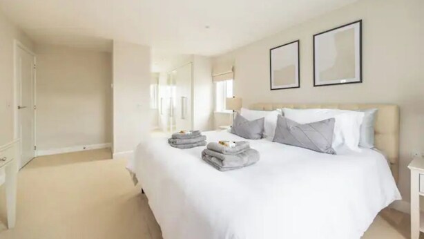 Quarto de hotel com uma cama grande, uma mesinha de cabeceira e um guarda-roupa.