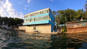 Un immeuble à plusieurs étages, à la façade bleue, situé au bord d’un plan d’eau.