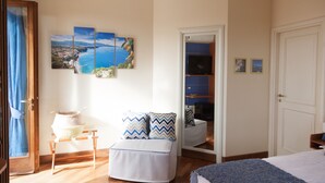 A bedroom with a bed, a bedside table, a chair, a wardrobe, and a large window with a view of the sea. - Resort Ravella: Lord Executive room (Sant´Agata sui Due Golfi)