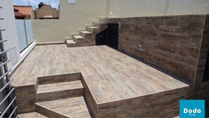 A rooftop terrace with a wooden floor and a set of stairs leading to a door. - Torre Altamar (Mazatlán)