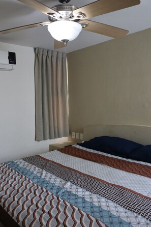 A bedroom with a bed, a ceiling fan, and a window with curtains. - Torre Altamar (Mazatlán)
