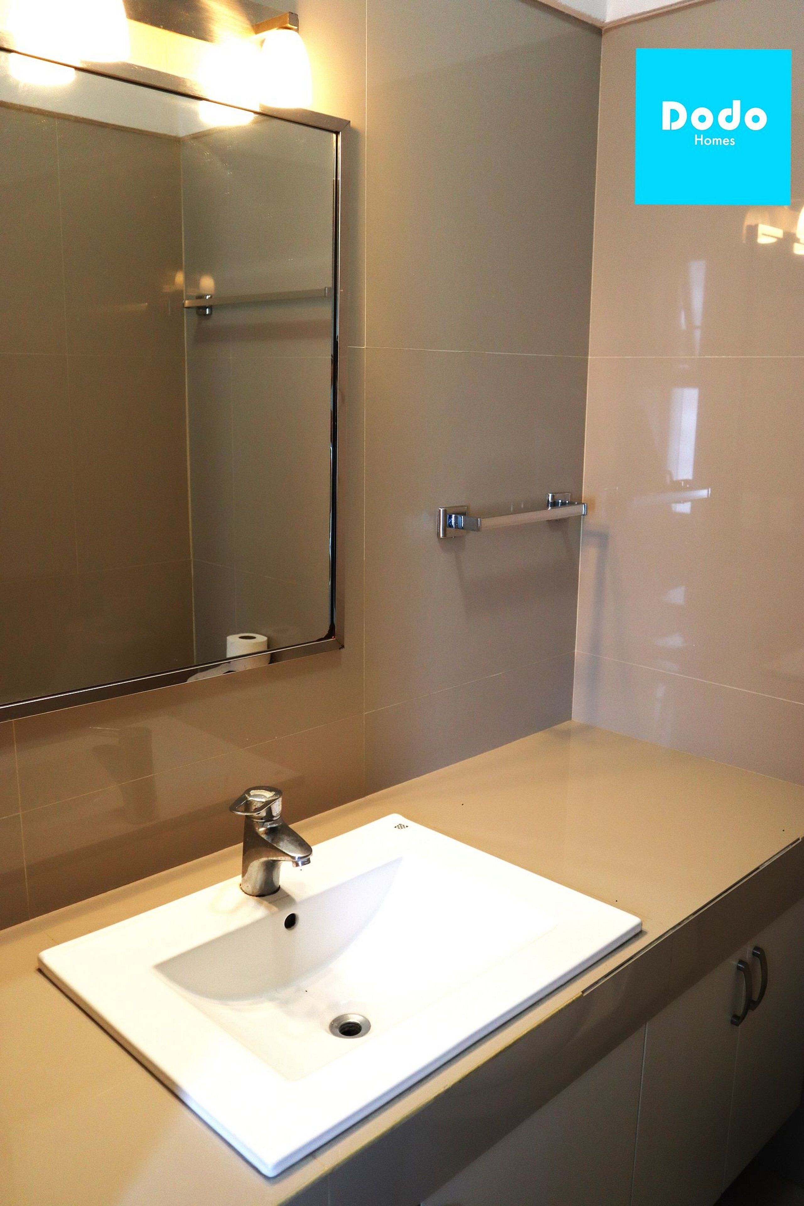 Casa de banho com lavatório branco, espelho e porta-toalhas.
