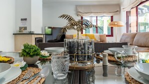 A dining area with a glass table, woven placemats, and a variety of glassware and decorative items.