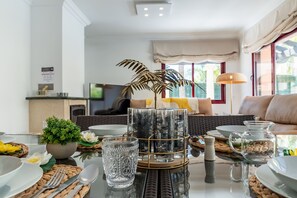 A dining area with a glass table, woven placemats, and a variety of glassware and decorative items.